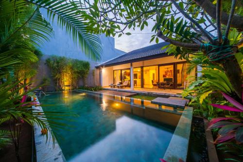 a swimming pool in front of a house at Tirta Villa in Sanur