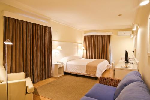 a hotel room with a bed and a couch at Vitória Hotel Convention Indaiatuba in Indaiatuba