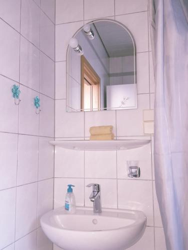 a white bathroom with a sink and a mirror at Ferienwohnung in Flörsheim