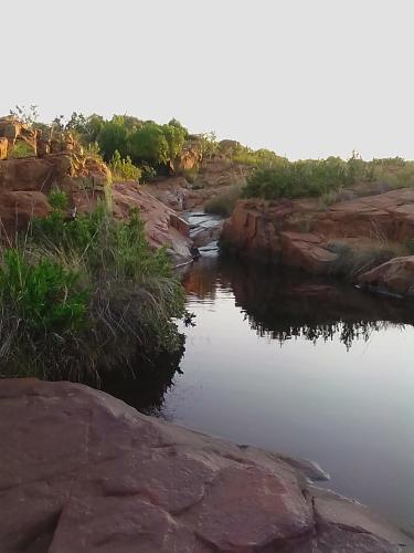 a river with rocks and trees in the background at Bateleur Nature Reserve in Modimolle
