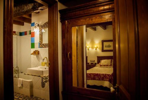 a bathroom with a sink and a bed and a mirror at Casería el Hondrígu in Mestas del Con