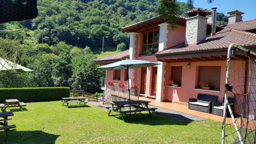 a house with picnic tables and an umbrella in the yard at Aptos La Corona-Cabrales-Picos de Europa in Carreña de Cabrales