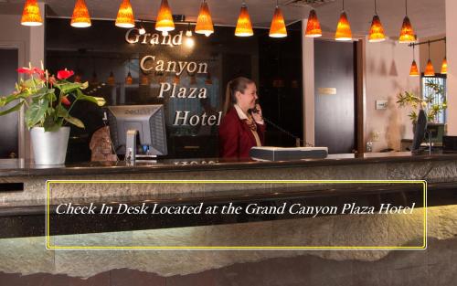 
a woman standing at a counter with a sign on it at Canyon Plaza Premier Studio and Apartments in Tusayan
