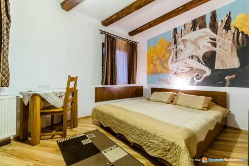 DrăguşにあるPensiunea Casa Zmeilorのベッドルーム1室(ベッド1台付)が備わります。壁には絵画が飾られています。