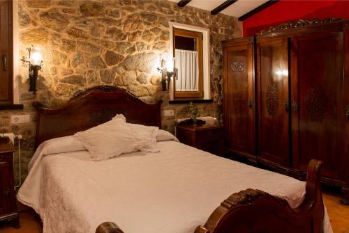 a bedroom with a bed and a stone wall at Hotel Rural Casa Fontequeiroso in Muxia