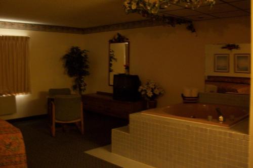 a room with a tub and a bed and a television at Lodi Valley Suites in Lodi