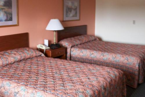 a hotel room with two beds and a lamp on a table at Lodi Valley Suites in Lodi