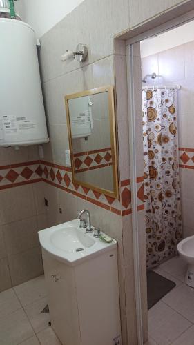 a bathroom with a sink and a toilet and a mirror at Departamentos céntricos con parrilla in Punta Alta