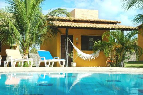 a resort with a swimming pool and chairs and a house at Hotel Enseada Maracajaú in Maracajaú