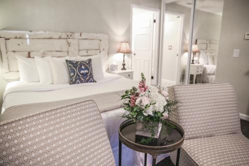 a bedroom with a bed and two chairs and a table with flowers at The Rigdon House in Cambria
