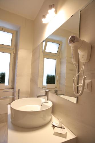 uma casa de banho com um lavatório e um secador de cabelo na parede em Khome Rooms & Apartment em Catânia