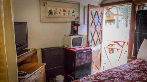 a room with a bed and a tv and a microwave at Cabins 4 Less, No Fees in Big Bear Lake