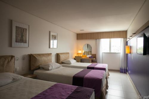 a hotel room with two beds with purple sheets at Iu-á Hotel in Juazeiro do Norte