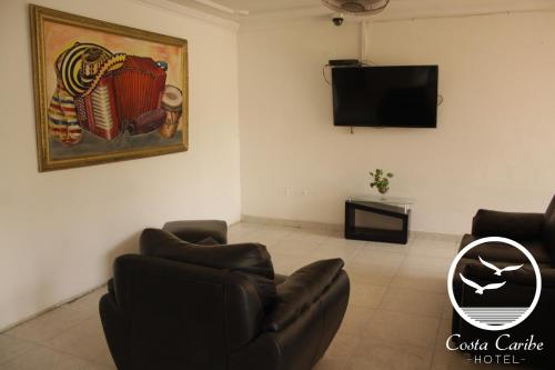 a living room with a couch and a flat screen tv at Hotel Costa Caribe in Barranquilla