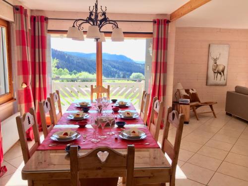 une salle à manger avec une table et une grande fenêtre dans l'établissement Chalet Le Flocon Bleu - Mauselaine avec vue sur le Lac de Gérardmer, à Gérardmer