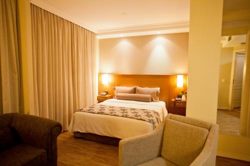 um quarto de hotel com uma cama e uma cadeira em The World Vila Olímpia em São Paulo