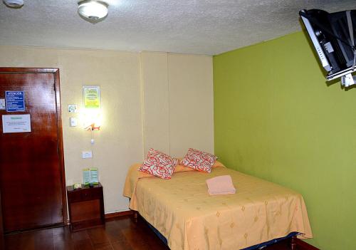 a bedroom with a bed with two pillows on it at Hostal Terra 2 - EL CONDADO in Quito