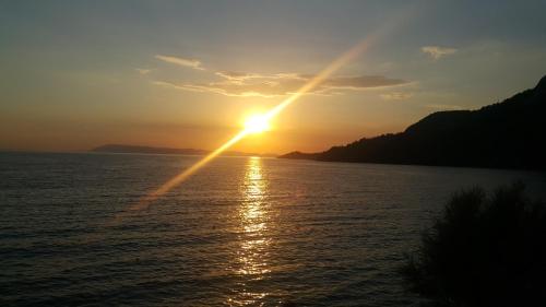 a sunset over the water with the sun in the sky at Apartments Alać in Drasnice