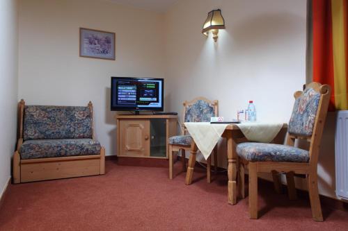 Cette chambre dispose d'une table, d'une télévision et de chaises. dans l'établissement Hotel Sieweburen, à Luxembourg