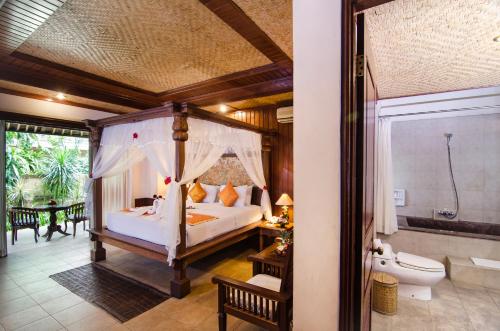a bedroom with a canopy bed and a bathroom at Sri Phala Resort & Villa in Sanur