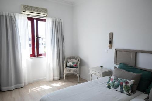 a bedroom with a bed and a chair and a window at Ericeira Lounge Seaside Apartment in Ericeira