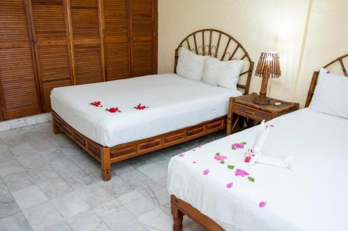 2 camas en una habitación con flores en las sábanas en Villa Diamante en Zihuatanejo