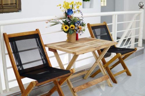 a wooden table and two chairs with a vase of flowers at Avocado house in Quy Nhon