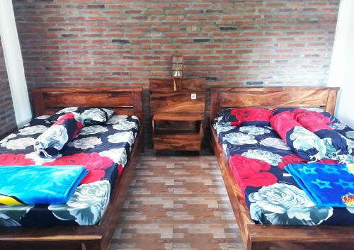 Ragha Homestay في Batukaras: سريرين في غرفة مع جدار من الطوب