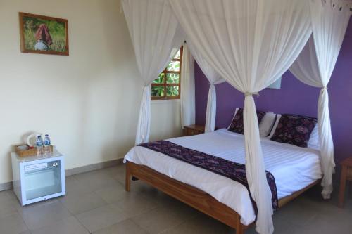 ein Schlafzimmer mit einem Himmelbett und einem Fenster in der Unterkunft Golo Hilltop Hotel in Labuan Bajo