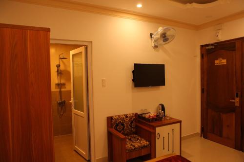 a room with a tv on the wall and a chair at Dalat Luxury Hotel in Da Lat