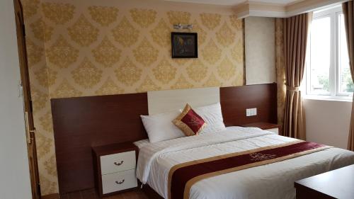 a bedroom with a bed and a window at Dalat Luxury Hotel in Da Lat