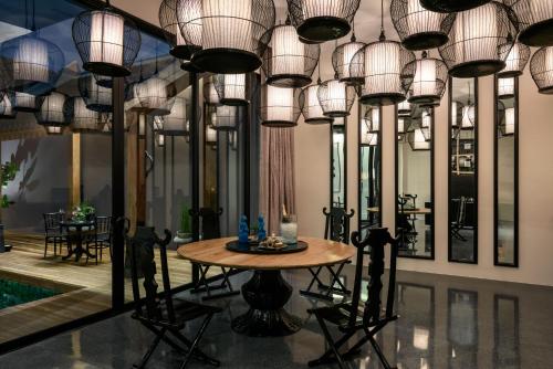 a dining room with a table and chandeliers at The Secret Pool Villas By The Library Koh Samui in Chaweng