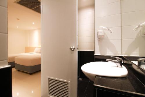 ein Bad mit einem Waschbecken und ein Bett in einem Zimmer in der Unterkunft Ten Stars Hotel in Bangkok