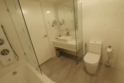 a bathroom with a toilet and a sink and a shower at Hotel Carlito Tagaytay in Tagaytay