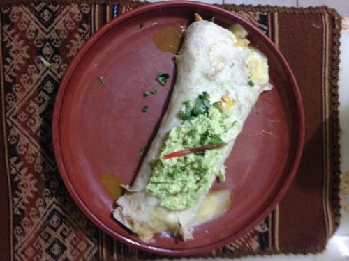 a red plate with a slice of pizza with guacamole at La Casa de Zarela in Huaraz
