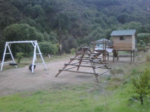 a group of picnic tables and swings in a field at Refugios Olmue Santa Teresa in El Maqui