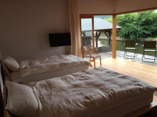 een slaapkamer met 2 bedden en een balkon met een televisie bij Waterside Cottage Heron in Kyotango