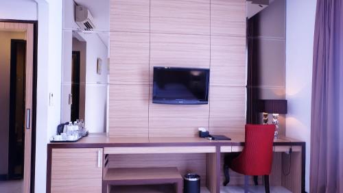 a room with a desk with a tv on a wall at Royal Hotel Bogor in Bogor