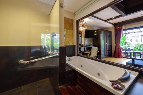 a bathroom with a tub and a large mirror at Samui Jasmine Resort - SHA Plus in Lamai