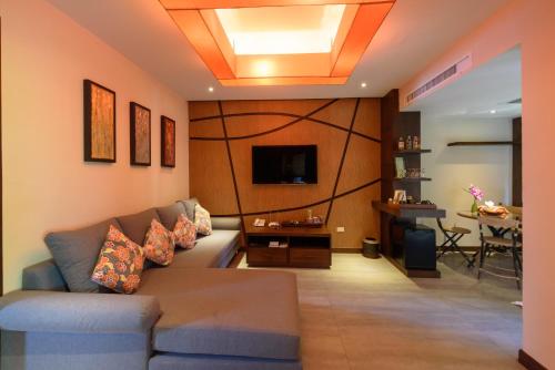 a living room with a couch and a television at Samui Jasmine Resort - SHA Plus in Lamai
