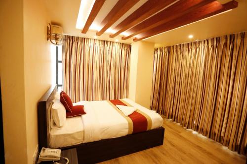 a bedroom with a bed and a window with curtains at Hotel Readers Inn Pvt.Ltd in Kathmandu