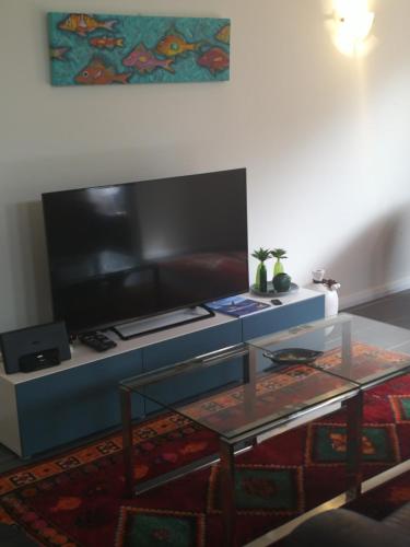 a living room with a flat screen tv and a table at Villa 28 Cape Villas in Dunsborough