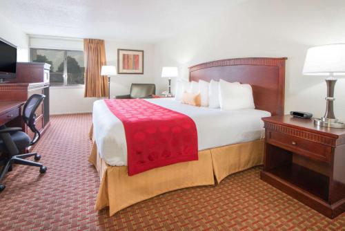 a hotel room with a large bed and a desk at Ramada by Wyndham Enid in Enid