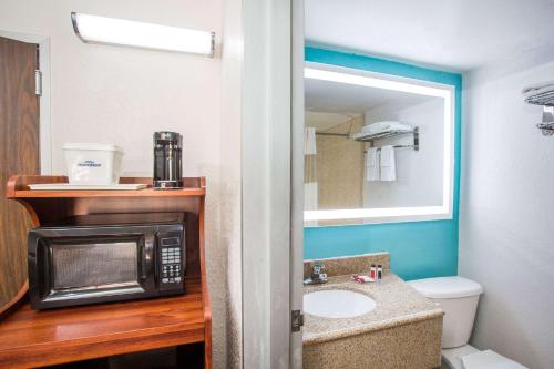 a small bathroom with a microwave and a sink at Howard Johnson by Wyndham Winter Haven FL in Winter Haven