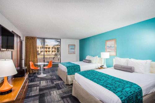 duas camas num quarto de hotel com paredes azuis em Howard Johnson by Wyndham Winter Haven FL em Winter Haven