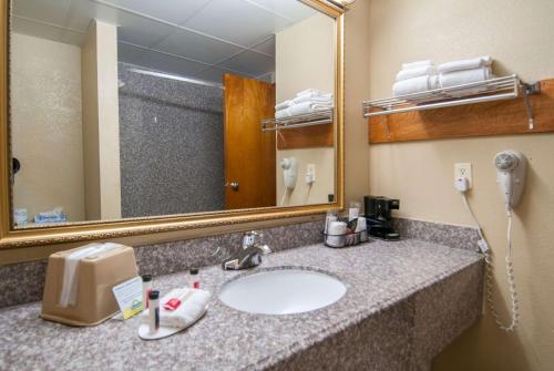 a bathroom with a sink with a mirror and a phone at Days Inn by Wyndham Pauls Valley in Pauls Valley