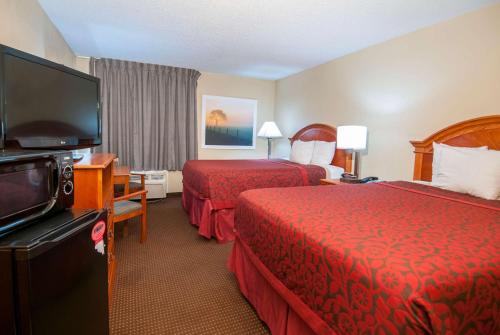 a hotel room with two beds and a flat screen tv at Days Inn by Wyndham Pauls Valley in Pauls Valley