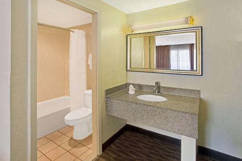 a bathroom with a sink and a toilet and a mirror at Days Inn by Wyndham Silver Spring in Silver Spring