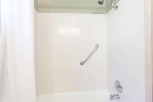 y baño con ducha y pared blanca. en Travelodge by Wyndham Everett City Center, en Everett