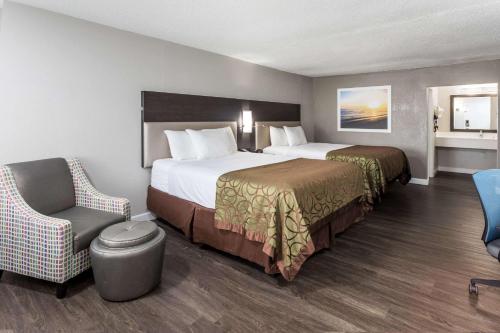a hotel room with two beds and a chair at Days Inn by Wyndham Goose Creek in Charleston